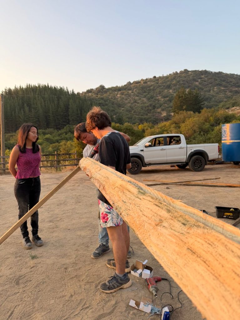 Grupo de voluntarios y colaboradores de Fundación Equicentro sonriendo en las afueras de un establo de madera en Pencahue, compartiendo una jornada de trabajo comunitario bajo el sol del Maule.