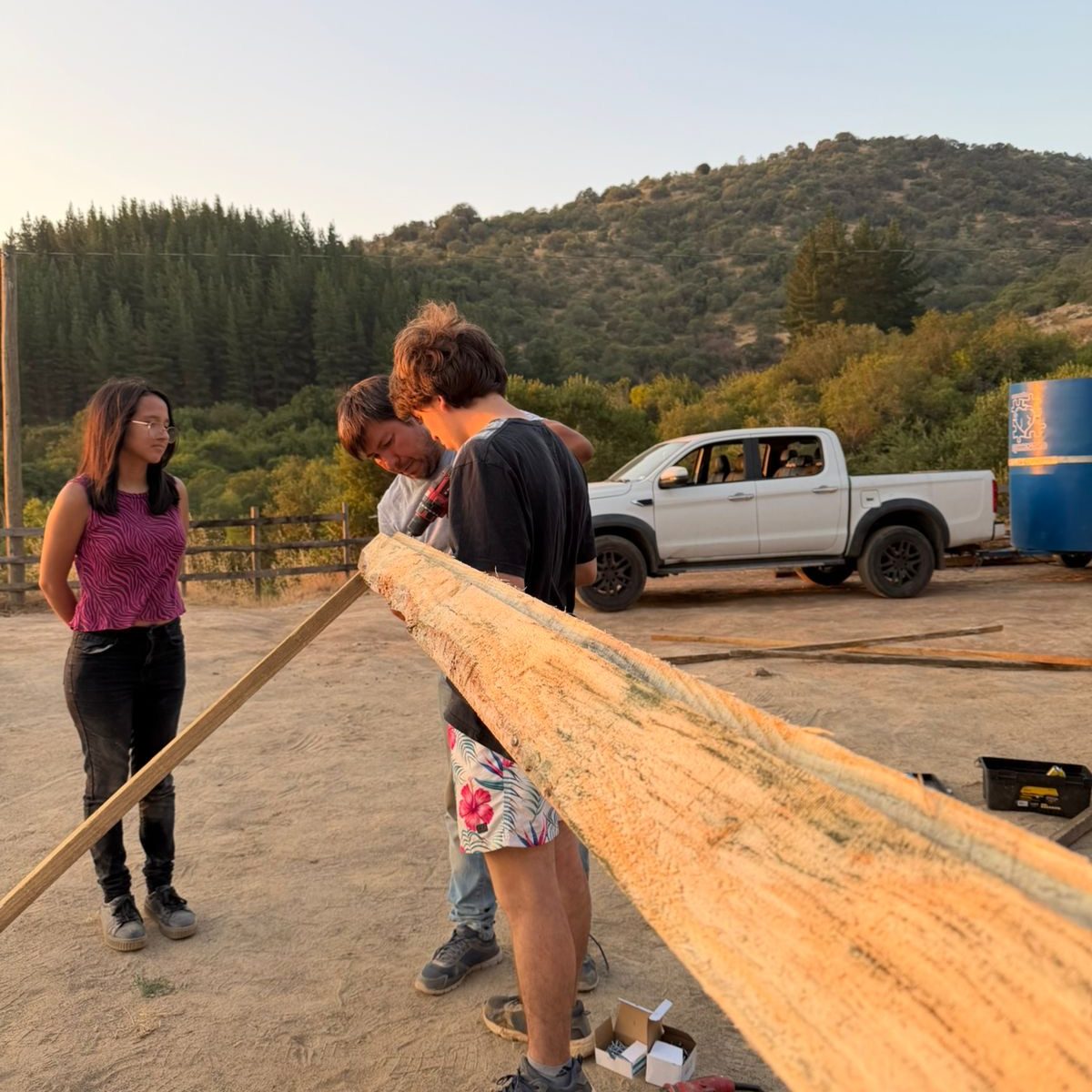 Grupo de voluntarios y colaboradores de Fundación Equicentro sonriendo en las afueras de un establo de madera en Pencahue, compartiendo una jornada de trabajo comunitario bajo el sol del Maule.